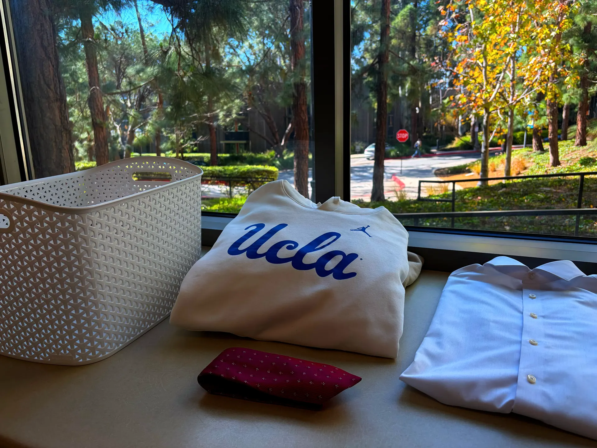 Folded UCLA apparel and a laundry basket on a window ledge overlooking campus